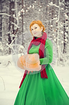 Fiery red-haired woman in a ball green dress with a red leather belt in the costume of dwarf assistant Santa Claus in the winter f
