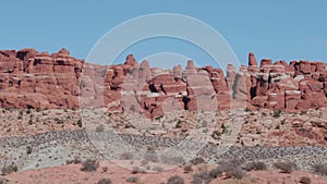 Fiery red massive rock pinnacles formation in arches park on sunny day in motion