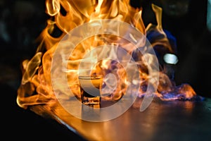 Fiery show at the bar. The bartender makes hot alcoholic cocktail and ignites bar. Fire on bar. glass with an alcoholic drink on