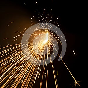 Fiery sparks exploding from a bright light source at night