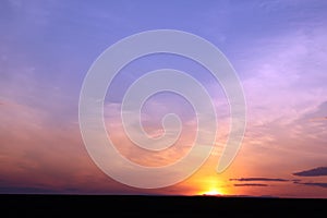 Fiery sun, light rays and beautiful clouds at sunset.