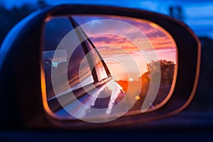 Fiery sunset as seen on the car`s side mirror