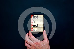 FIFO first in first out symbol. Concept words FIFO first in first out on wooden blocks. Beautiful black table, black background.