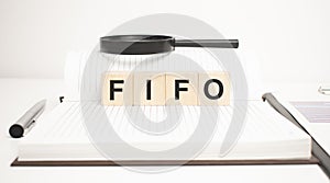 fifo word concept. wooden cubes, notepad, pen and business charts