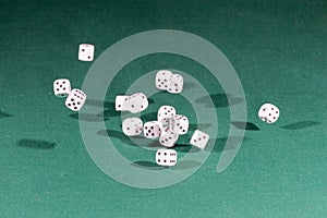 Fifteen white dices falling on a green table