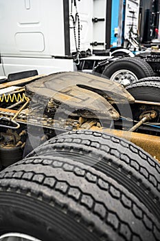 Fifth wheel truck coupling and rear suspension and wheels of big rigs semi trucks standing in row on the parking lot