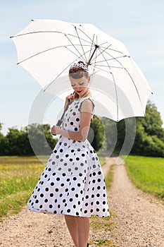 Fifties look with petticoat dress, hairband and sunshade in the photo