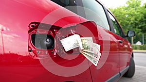Fifty dollar bills in a bundle attached to an open fuel tank of a car