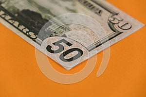 fifty dollars lying on orange background close up