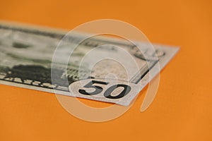 fifty dollars lying on orange background close up
