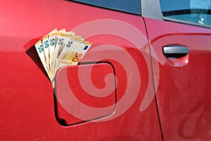 Fifty euro notes sticking out of a car's closed fuel tank