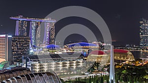 Fifty-five storeys high Marina Bay Sands Hotel dominates the skyline at Marina Bay in Singapore aerial night timelapse.