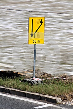 Fifty meters ahead yellow redirection road sign mounted on metal pole and heavy foundation at local road construction site photo