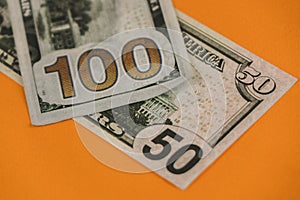 fifty and one hundred dollars lying on an orange background close up