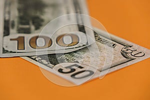 fifty and one hundred dollars lying on an orange background close up