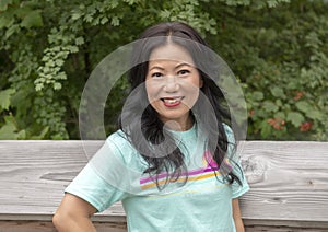 Fifty-three year-old Korean woman posing on a wooden bridge in the Washington Park Arboretum, Seattle, Washington