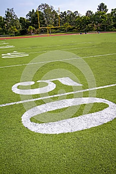 Fifty yard line on football field with goal post in distance