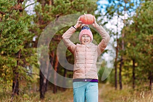 Fifty-year-old beautiful woman in a hat and jacket and orange pumpkin outdoors. harvest in autumn