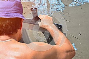 Fifty years old manual worker with wall plastering tools renovating house