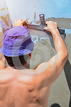 Fifty years old manual worker with wall plastering tools renovating house