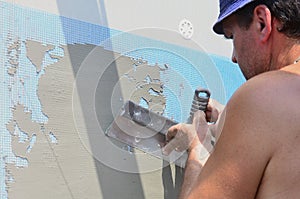 Fifty years old manual worker with wall plastering tools renovating house