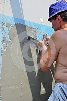 Fifty years old manual worker with wall plastering tools renovating house