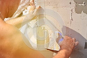 Fifty years old manual worker with wall plastering tools renovating house