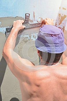 Fifty years old manual worker with wall plastering tools renovating house. Plasterer renovating walls and corners with spatula and
