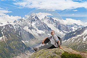 Fifty years tourists sitting on a rock against mountain summits