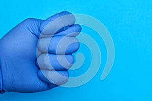 Fig as a gesture from a hand in a glove on a blue background