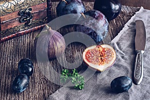 The fig is cut on a wooden table with grapes and plums. Still life with figs. Selective focus