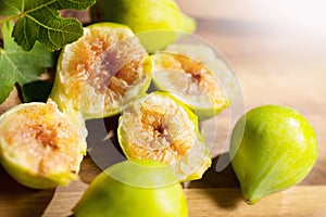 Fig fruits macro shot. Ripe sweet yellow and green figs fruit with leaves on wooden table close up