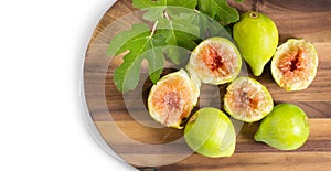 Fig fruits. Ripe sweet yellow and green figs fruit with leaves on wooden table close up, isolated on white