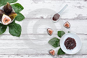 Fig jam with figs, fig leaves and white spoon with jam on White wood background