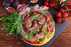 Fig pizza with bacon, green pimiento olives, rocket and basil leaves