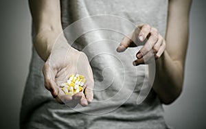 The fight against drugs and drug addiction topic: addict holding a narcotic pills on a dark background