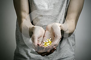 The fight against drugs and drug addiction topic: addict holding a narcotic pills on a dark background