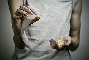 The fight against drugs and drug addiction topic: addict holding a narcotic pills on a dark background photo