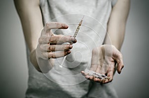 The fight against drugs and drug addiction topic: skinny dirty addict holding a syringe with a drug and red heart on a dark