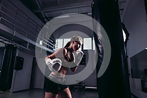 Fighter girl wearing sportswear punching bag