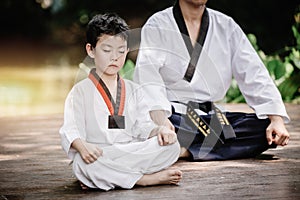 Fighter kid in Taekwondo uniform sitting concentration for training self defense body and mild