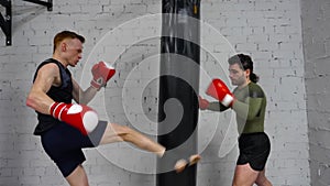 Fighter man in boxing gloves making blows on combat bag while personal training. Fitness trainer training man boxing