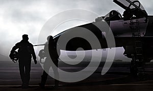 Fighter pilot and jet on military airbase at dawn