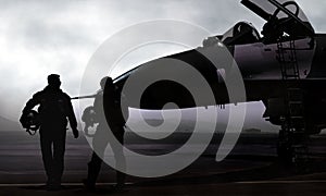 Fighter pilot and jet on military airbase at dawn photo