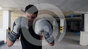 Fighter practicing punches on boxing bag at the parking zone, closeup