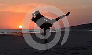 A fighter training on the beach at sunset