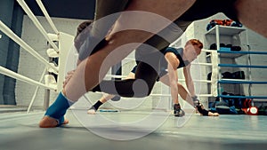 Fighters doing stretching legs before boxing training on box ring in fight club