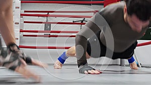 Fighters make push ups with claps on the floor on training on ringside.