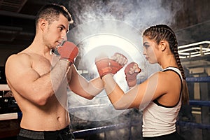 Fighting caucasian people, man and woman together in boxing ring