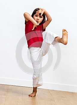 Fighting child raising feet and playing hands to practise taekwondo